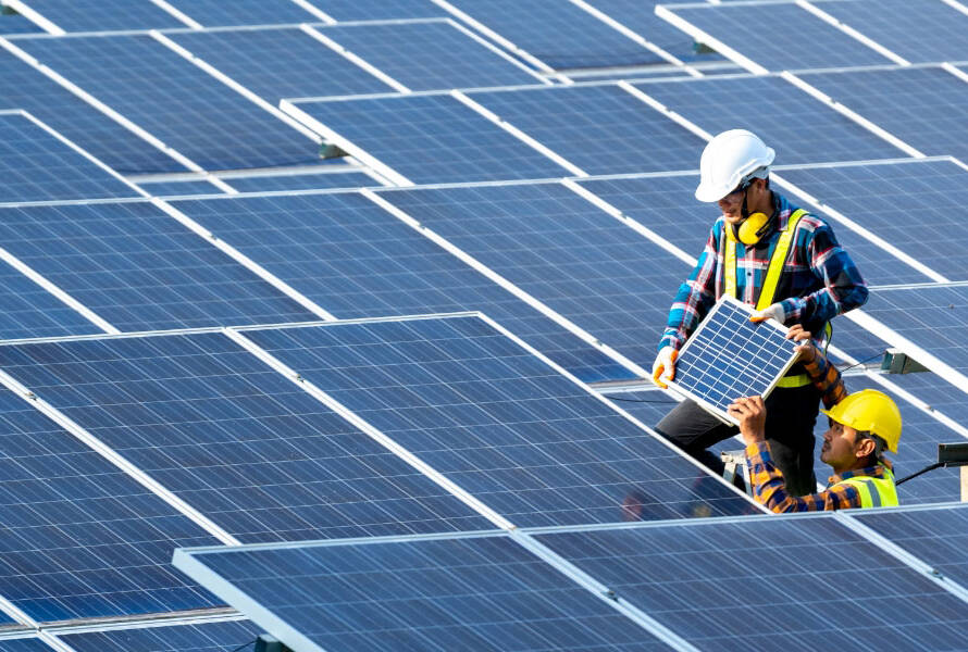 Danışmanımız, müşteri ile güneş enerji sistemlerinin planlanması hakkında masada oturarak konuşurken. Etrafta güneş paneli tasarımları ve verimlilik grafikleriyle dolu belgeler bulunmaktadır, bu da sürecin her yönüyle detaylı bir şekilde ele alındığını gösterir.