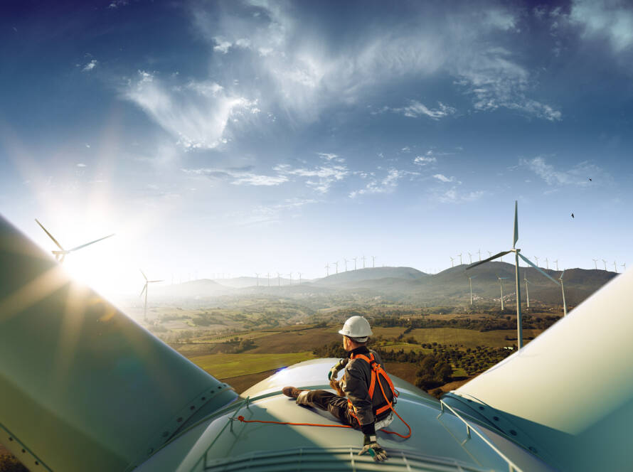 Güneş enerji sistemlerinin proje bazında planlanması, bir masa üzerinde yayılmış mavi çizimlerle ve veri analizleriyle dolu bir ekranın önünde çalışan bir mühendis tarafından gösterilmekte. Mühendis, sistem verimliliğini optimize etmek için detaylı hesaplamalar yapmaktadır.